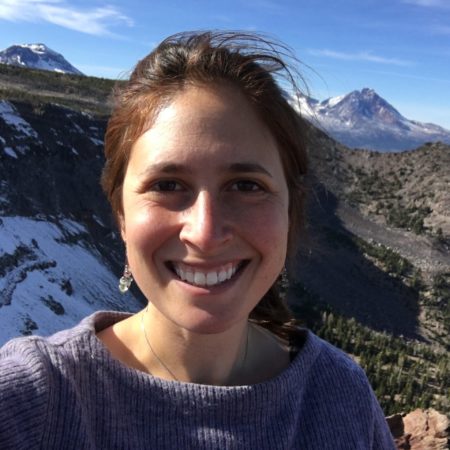 Forward Montana staff member Abby Sophir, smiling in front of mountain background scene