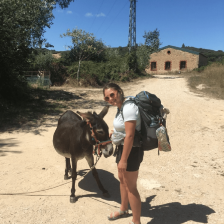 Forward Montana staff Grace standing on dirt road with small donkey